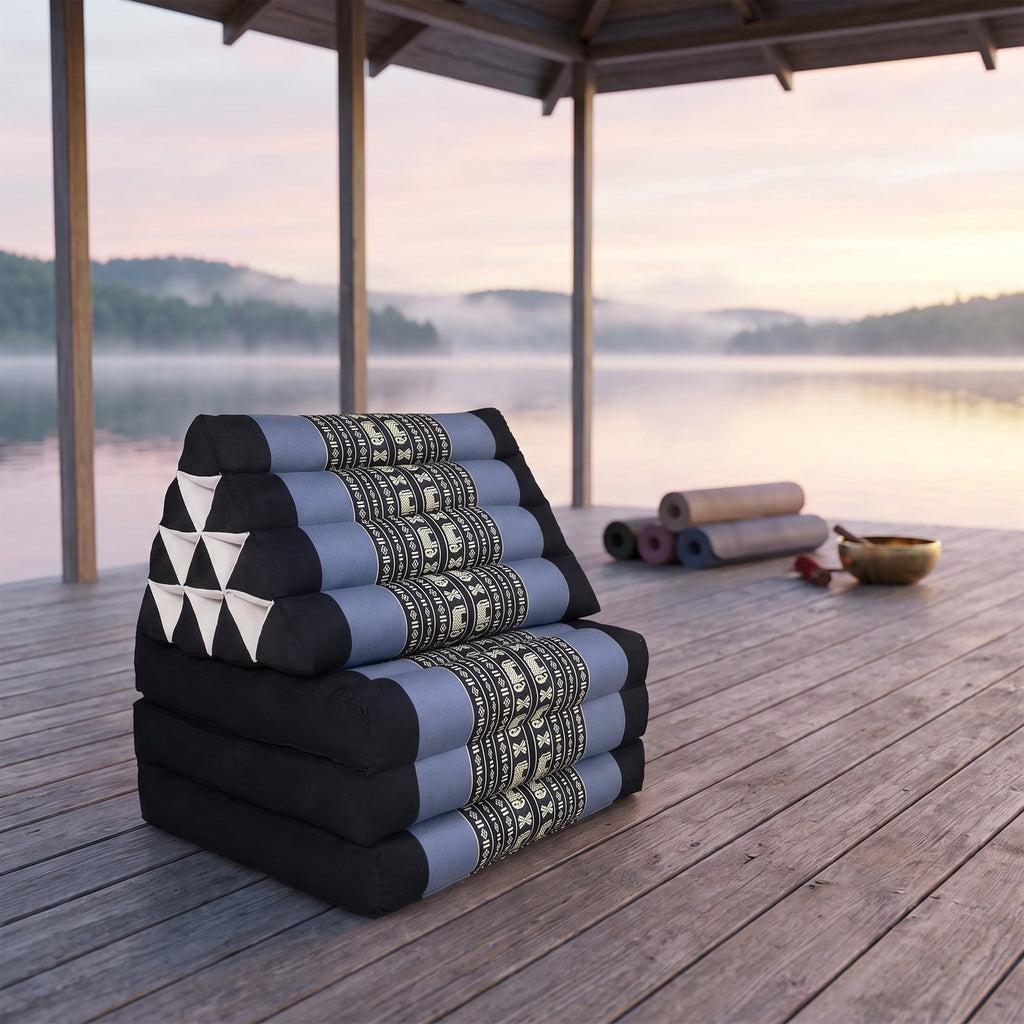 Blue elephant pattern Thai triangle floor mattress daybed, folded, on a lakeside pavilion at dawn