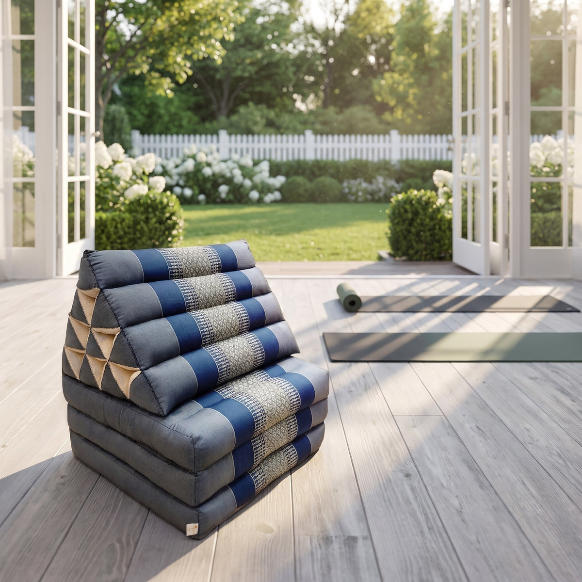Grey-blue Thai triangle floor mattress daybed, folded, in a garden yoga studio