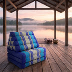 Navy Thai triangle floor mattress daybed, folded, on a lakeside pavilion at dawn