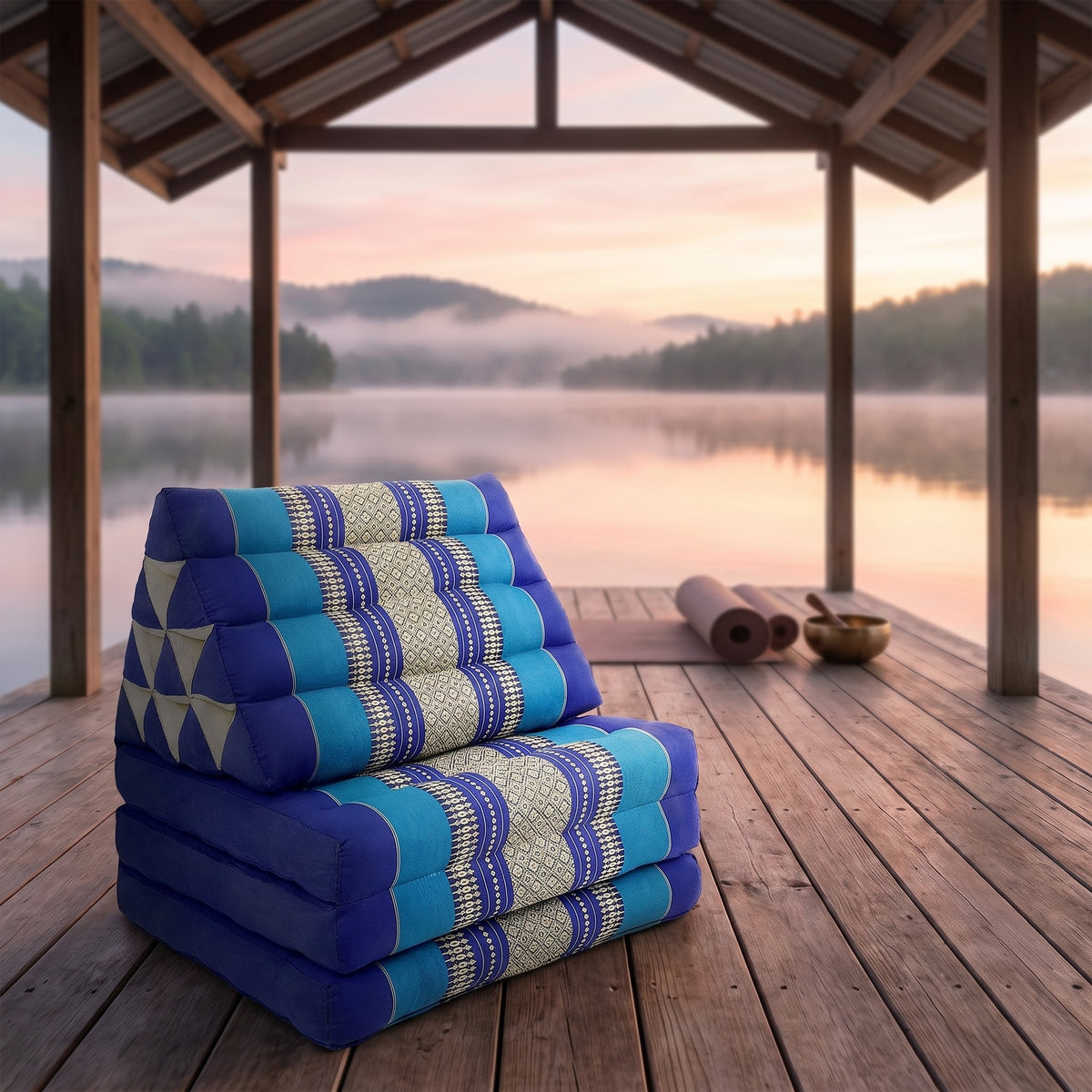 Navy Thai triangle floor mattress daybed, folded, on a lakeside pavilion at dawn