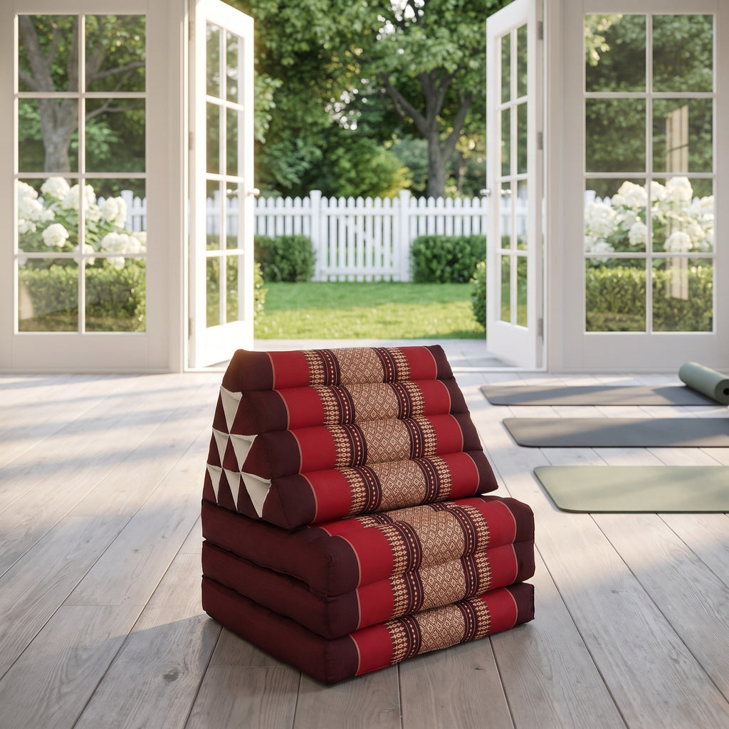 Red Thai triangle floor mattress daybed, folded, in a garden yoga studio