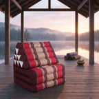 Red Thai triangle floor mattress daybed, folded, on a lakeside pavilion at dawn