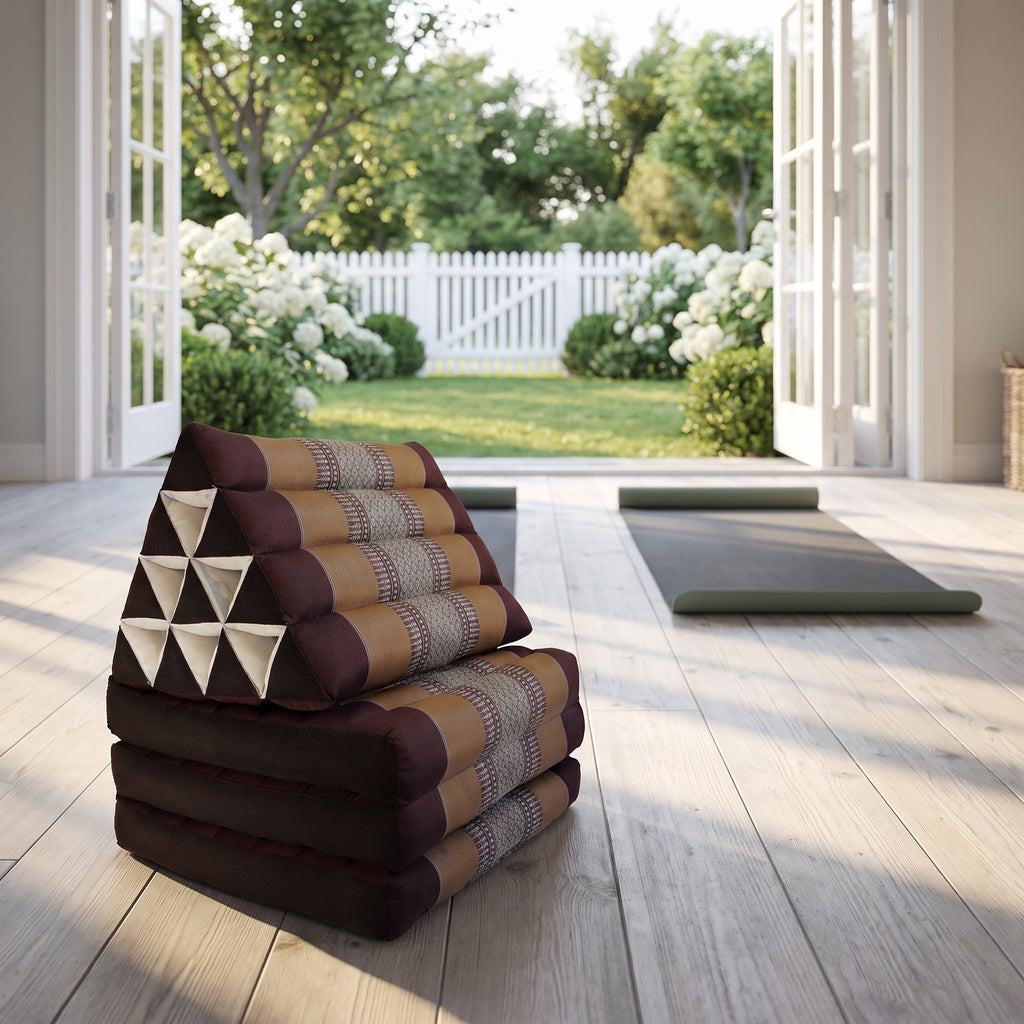 Brown Thai triangle floor mattress daybed, folded, in a garden yoga studio