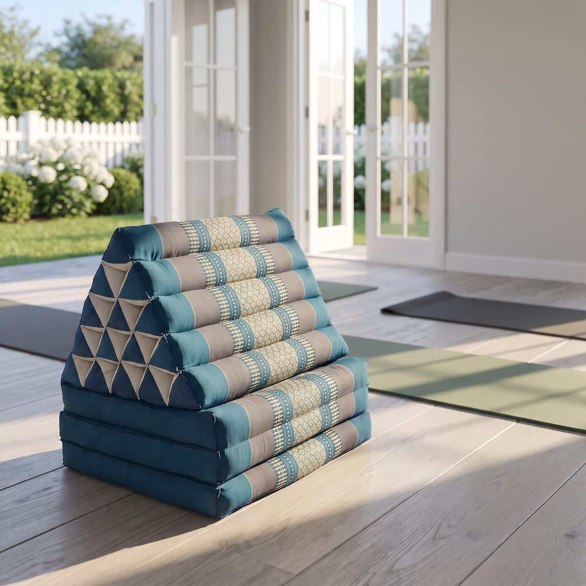 Blue Jumbo 3-fold Thai triangle floor mattress, folded, in a garden yoga studio