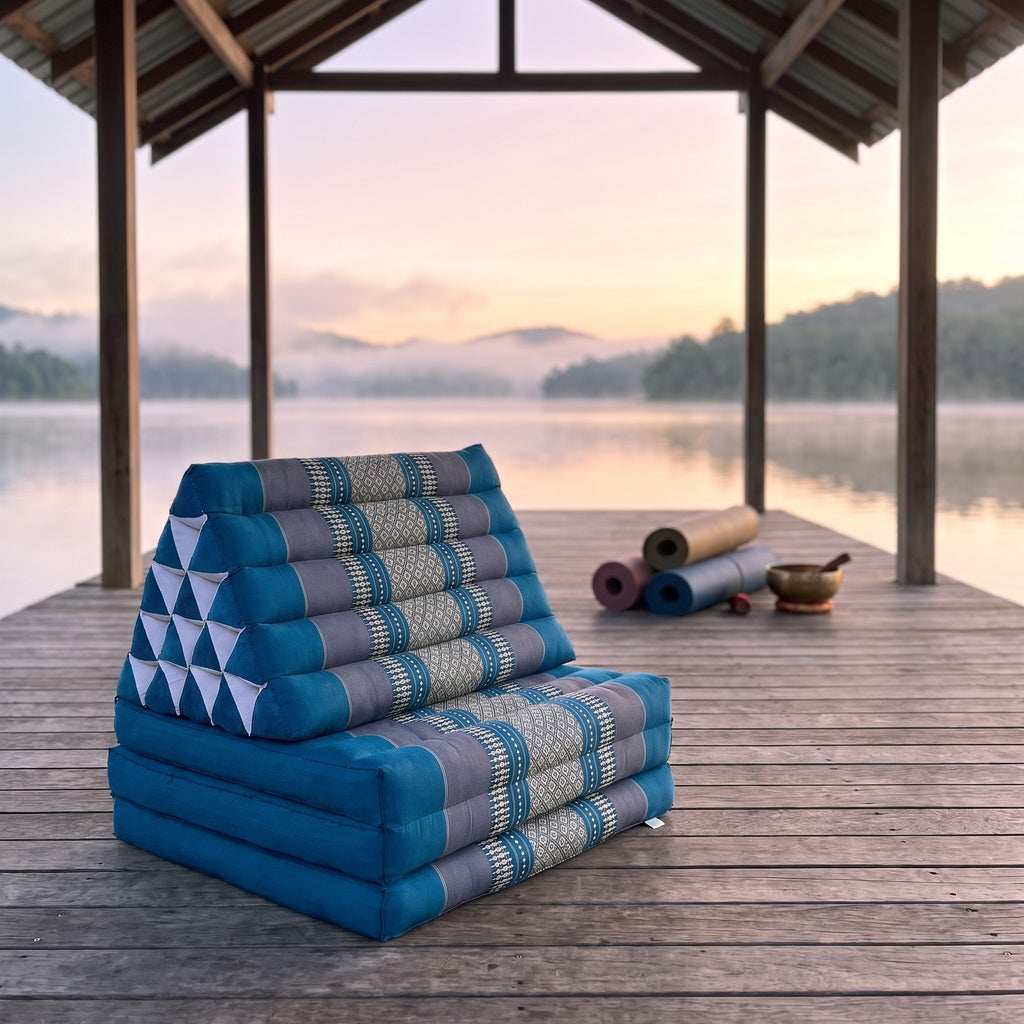 Blue Jumbo 3-fold Thai triangle floor mattress, folded, on a lakeside pavilion at dawn