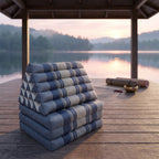 Grey-blue Jumbo 3-fold Thai triangle floor mattress, folded, on a lakeside pavilion at dawn