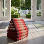 Red Jumbo 3-fold Thai triangle floor mattress, folded, in a garden yoga studio