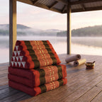 Red Elephant Jumbo 3-fold Thai triangle floor mattress, folded, on a lakeside pavilion at dawn
