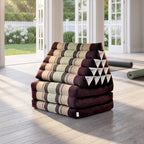 Brown Jumbo 3-fold Thai triangle floor mattress, folded, in a garden yoga studio