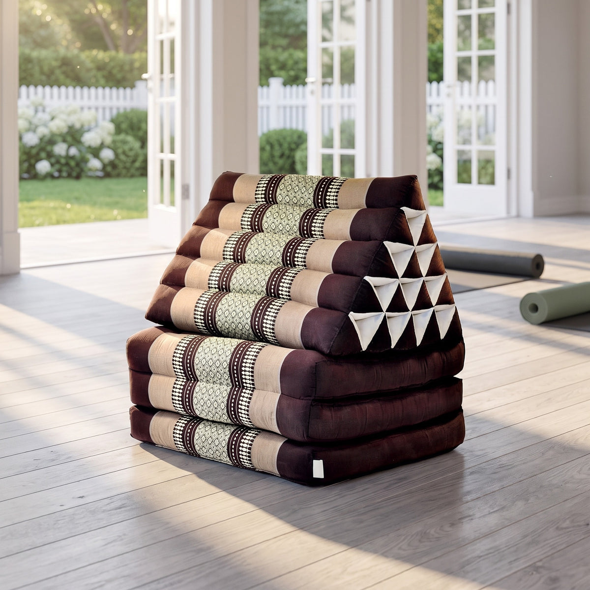 Brown Jumbo 3-fold Thai triangle floor mattress, folded, in a garden yoga studio