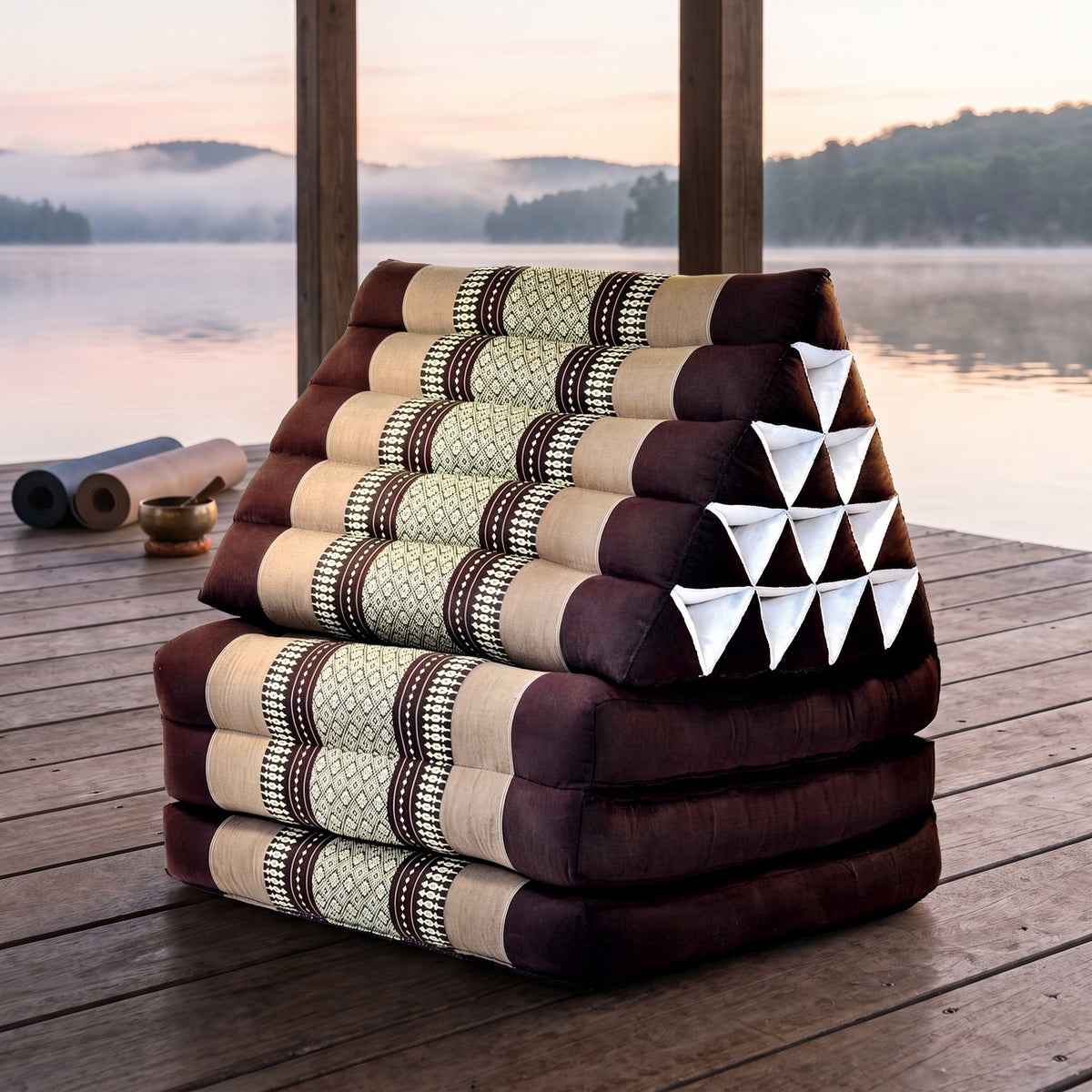 Brown Jumbo 3-fold Thai triangle floor mattress, folded, on a lakeside pavilion at dawn